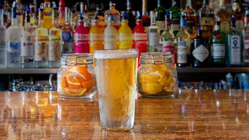 Beer in a pint glass on top of bar top